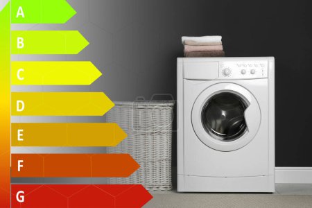 Foto de Etiqueta de eficiencia energética y lavadora con lavandería cerca de la pared negra en interiores - Imagen libre de derechos