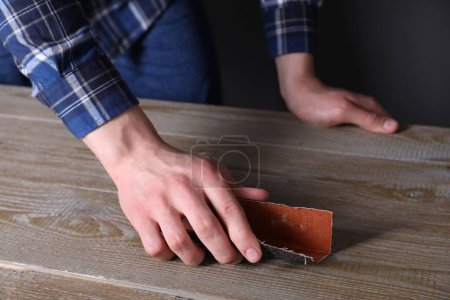 Foto de Hombre pulido mesa de madera con papel de lija, primer plano - Imagen libre de derechos