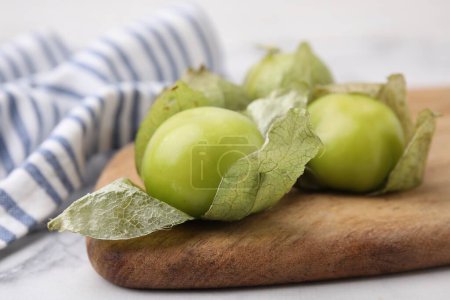 Frische grüne Tomatillos mit Schale auf hellem Tisch, Nahaufnahme