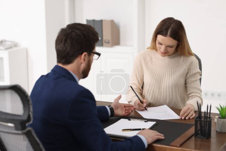 Photo for Woman signing document while having meeting with lawyer in office - Royalty Free Image