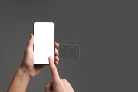 Mann mit Smartphone mit leerem Bildschirm auf grauem Hintergrund, Nahaufnahme. Mockup für Design