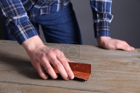 Foto de Hombre pulido mesa de madera con papel de lija, primer plano - Imagen libre de derechos