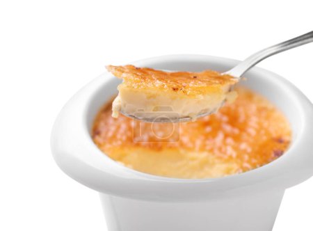 Foto de Tomando deliciosa crema brulee con cuchara de tazón sobre fondo blanco - Imagen libre de derechos