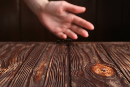 Woman holding hand above wooden table, selective focus. Space for text