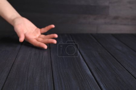 Frau hält Hand über schwarzem Holztisch, selektiver Fokus. Raum für Text