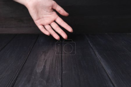 Frau hält Hand über schwarzem Holztisch, selektiver Fokus. Raum für Text