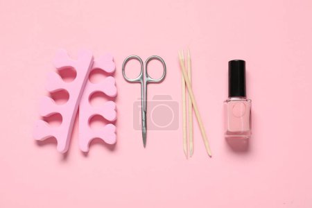 Foto de Esmalte de uñas, palos naranjas, tijeras y separadores de dedos sobre fondo rosa, posición plana - Imagen libre de derechos