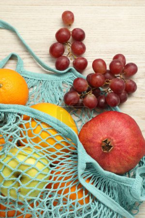 Téléchargez les photos : Sac à ficelle avec fruits frais sur fond bois blanc, vue de dessus - en image libre de droit