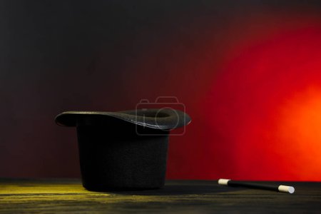 Zauberhut und Zauberstab auf Holztisch vor dunklem Hintergrund, Platz für Text