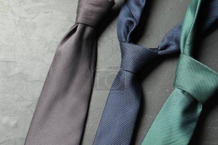 Different neckties on grey textured table, flat lay