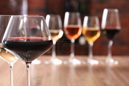 Photo for Tasty red and white wines in glasses against blurred background, space for text - Royalty Free Image