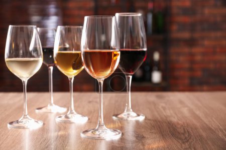 Photo for Different tasty wines in glasses on wooden table, space for text - Royalty Free Image