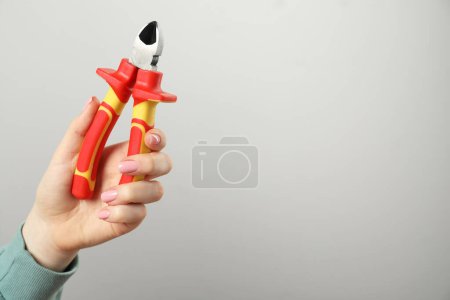 Photo for Woman with diagonal pliers on grey background, closeup. Space for text - Royalty Free Image