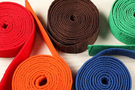 Colorful karate belts on wooden background, closeup