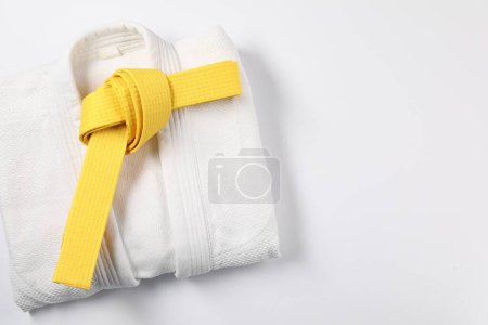 Photo for Yellow karate belt and kimono on white background, top view. Space for text - Royalty Free Image