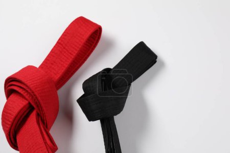 Red and black karate belts on white background, flat lay. Space for text