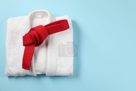 Photo for Red karate belt and white kimono on light blue background, top view. Space for text - Royalty Free Image