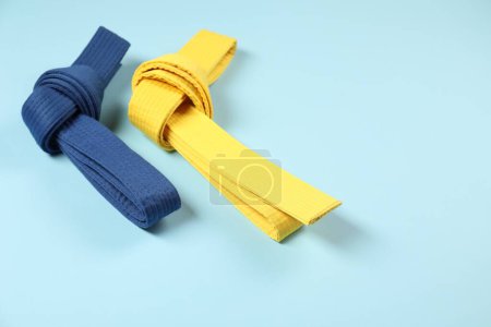 Photo for Colorful karate belts on light blue background, space for text - Royalty Free Image