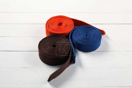 Cinturones de karate de colores sobre fondo de madera. Uniforme de artes marciales