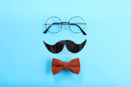Téléchargez les photos : Moustache artificielle, noeud papillon et lunettes sur fond bleu clair, pose plate - en image libre de droit