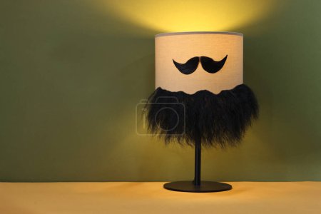 Téléchargez les photos : Visage d'homme fait de moustache artificielle, barbe et lampe sur fond kaki. Espace pour le texte - en image libre de droit