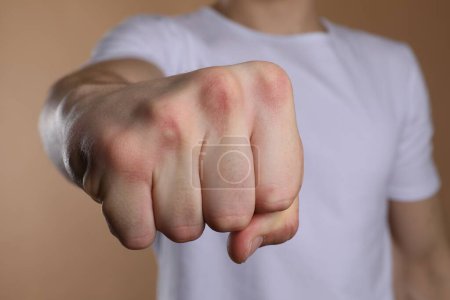 Man showing fist with space for tattoo on beige background, selective focus