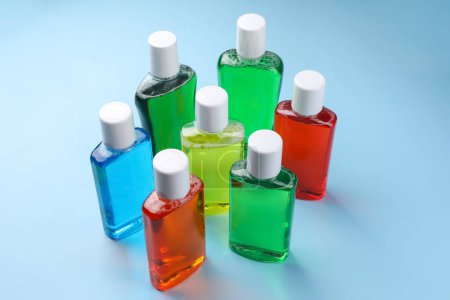 Frische Mundspülungen in Flaschen auf hellblauem Hintergrund