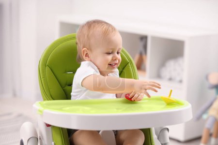 Photo for Children toys. Cute little boy playing with spinning tops in high chair at home - Royalty Free Image