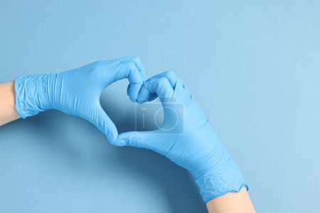 Téléchargez les photos : Médecin montrant un geste cardiaque avec les mains sur fond bleu clair, vue de dessus - en image libre de droit