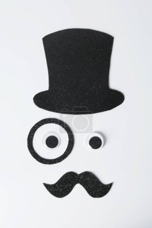 Téléchargez les photos : Visage d'homme en fausse moustache, chapeau, yeux et monocle sur fond blanc, vue de dessus - en image libre de droit