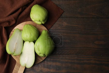 Photo for Cut and whole chayote on wooden table, flat lay. Space for text - Royalty Free Image