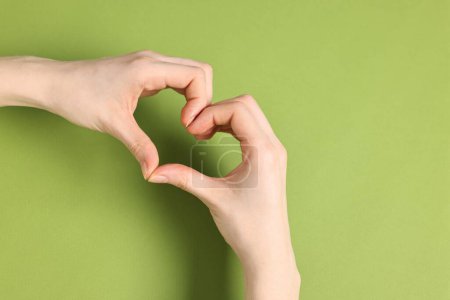 Téléchargez les photos : Femme montrant un geste de cœur avec les mains sur fond vert, vue de dessus. Espace pour le texte - en image libre de droit