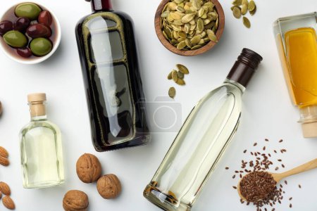 Foto de Grasas vegetales. Diferentes aceites en botellas de vidrio e ingredientes en mesa blanca, puesta plana - Imagen libre de derechos