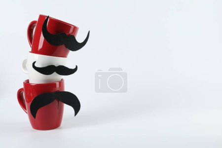 Téléchargez les photos : Tasses avec de fausses moustaches sur fond clair, espace pour le texte - en image libre de droit