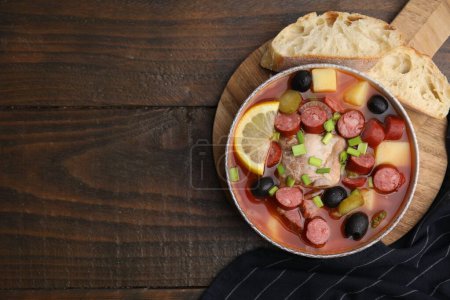 Téléchargez les photos : Soupe de viande solyanka avec de fines saucisses fumées sèches dans un bol et des tranches de pain sur une table en bois, à plat - en image libre de droit
