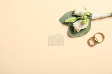Téléchargez les photos : Des mariages. Élégant boutonnière et anneaux sur fond beige, vue de dessus. Espace pour le texte - en image libre de droit