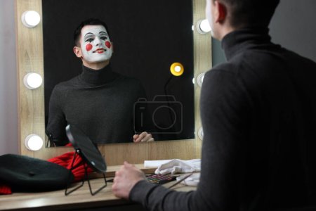 Mime artista posando cerca del espejo en el vestidor