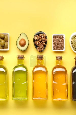 Foto de Grasas vegetales. Diferentes aceites en botellas de vidrio e ingredientes en la mesa amarilla, puesta plana - Imagen libre de derechos