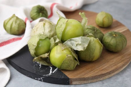 Tomatillos verts frais avec écorce sur table grise, gros plan