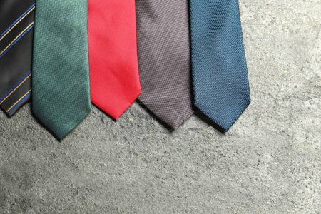 Different neckties on grey textured background, flat lay. Space for text