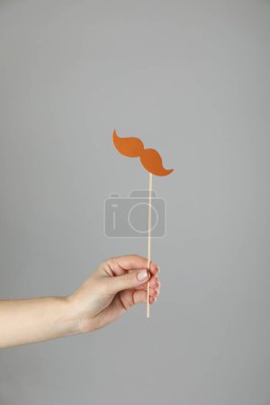 Téléchargez les photos : Femme avec fausse moustache en papier sur fond gris, gros plan - en image libre de droit
