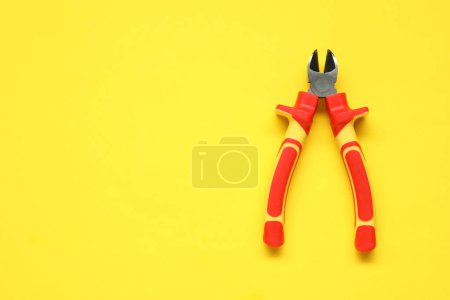 Photo for Diagonal pliers on yellow background, top view. Space for text - Royalty Free Image