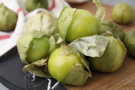 Tomates verdes frescos con cáscara en la mesa, primer plano