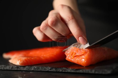 Téléchargez les photos : Chef enlevant les écailles du saumon pour les sushis à table noire, gros plan - en image libre de droit