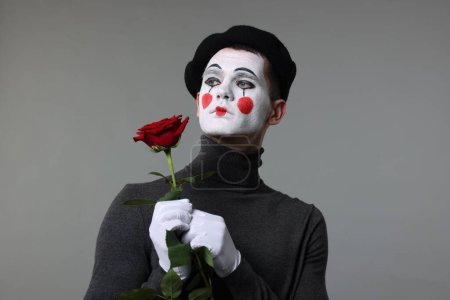 Porträt des Pantomimen mit roter Rose auf grauem Hintergrund