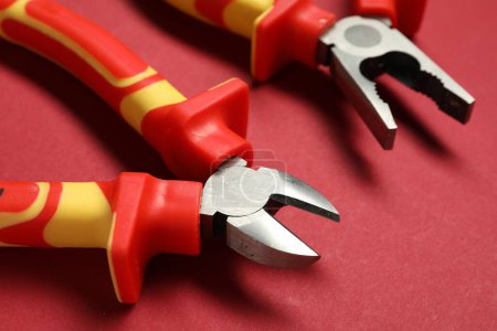 Photo for Two pliers on red background, closeup view - Royalty Free Image