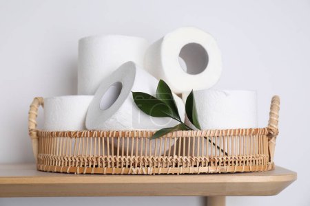 Téléchargez les photos : Rouleaux de papier toilette et feuilles vertes sur table en bois près du mur blanc - en image libre de droit
