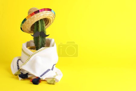 Téléchargez les photos : Cactus avec chapeau de sombrero mexicain, fausse moustache et poncho sur fond jaune, espace pour le texte - en image libre de droit
