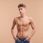 Shirtless man with slim body on beige background