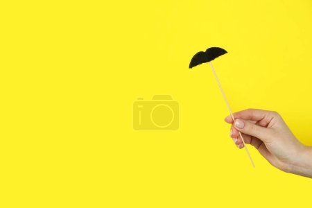 Téléchargez les photos : Femme avec une fausse moustache en papier sur fond jaune, gros plan. Espace pour le texte - en image libre de droit